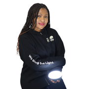 Person wearing a black zip hoodie featuring The Light Providers logo patch on the chest and We Bring the Light text down t...