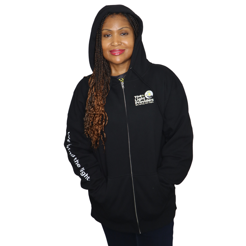 Model shown from a three quarter angle, wearing a black zip hoodie featuring The Light Providers logo patch on the chest a...