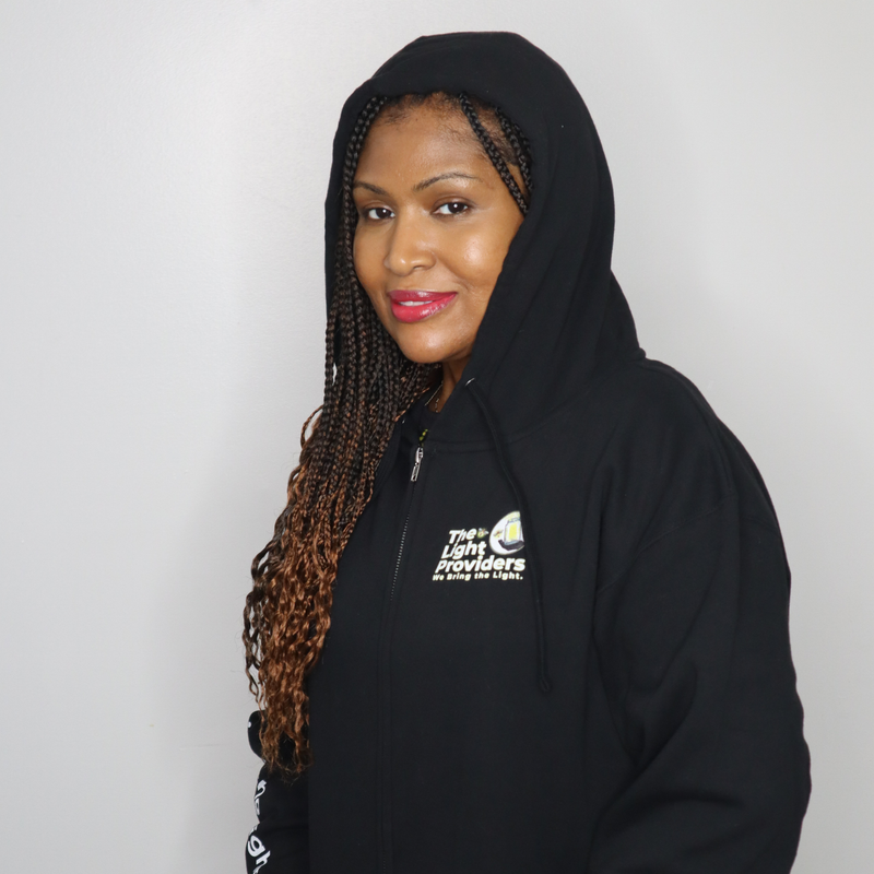 Model shown from the front, wearing a black zip hoodie featuring The Light Providers logo patch on the chest and We Bring ...