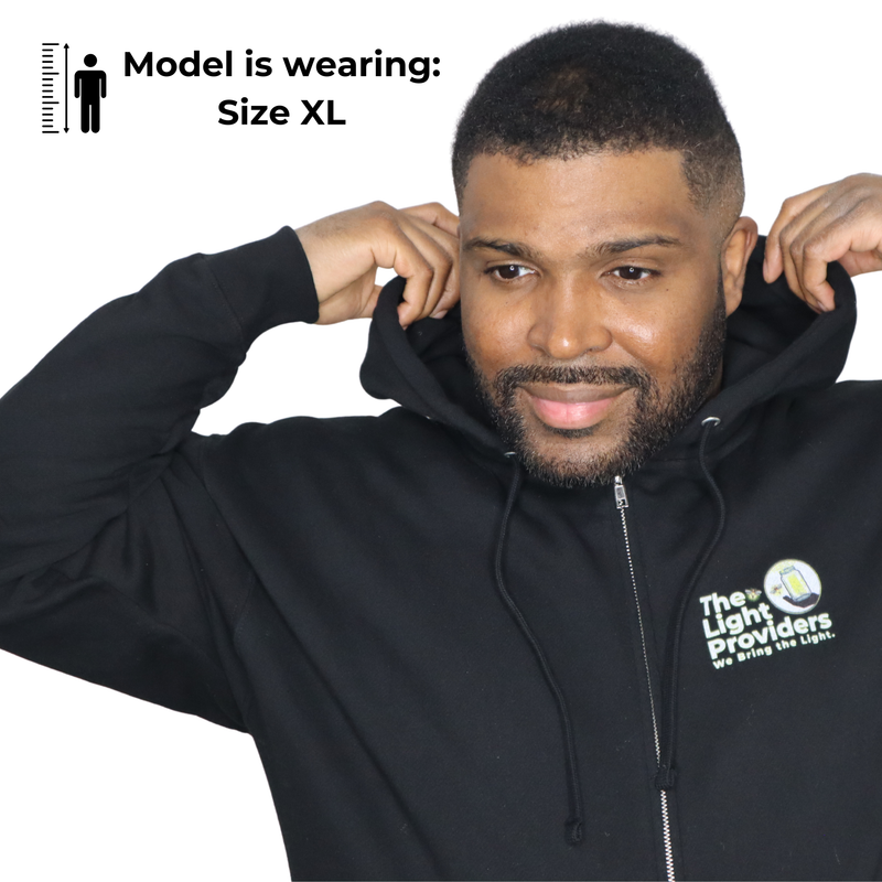 Model shown from a three quarter angle, wearing a black zip hoodie featuring The Light Providers logo patch on the chest a...