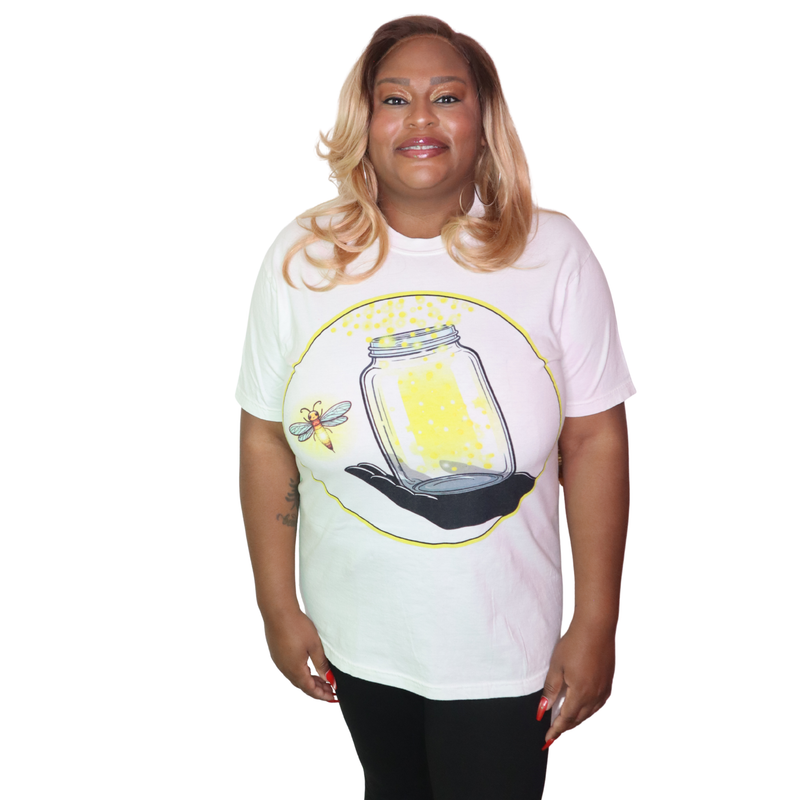 Person wearing a garment dyed t-shirt featuring The Light Providers logo and firefly jar graphic in white on the chest