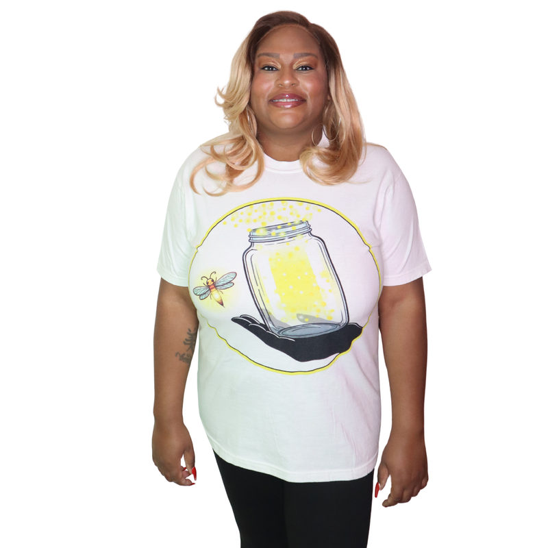 Model shown with arms crossed, wearing a garment dyed t-shirt featuring The Light Providers logo and firefly jar graphic i...
