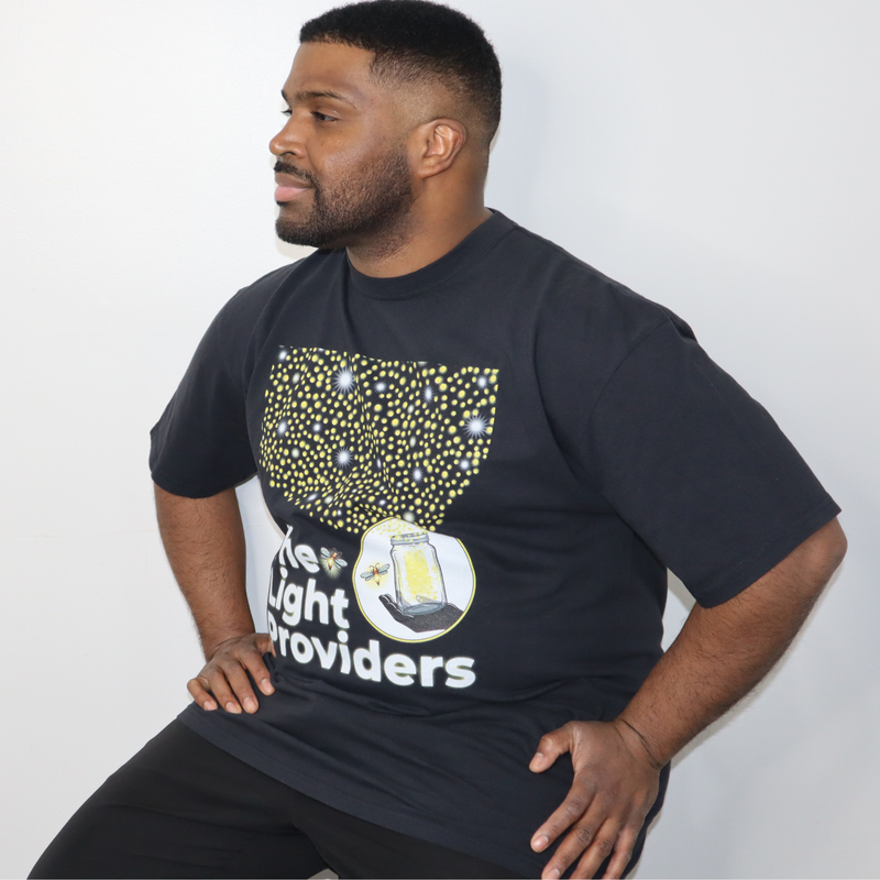 Model shown from the front, wearing a garment dyed t-shirt featuring a scattered firefly light pattern above The Light Pro...