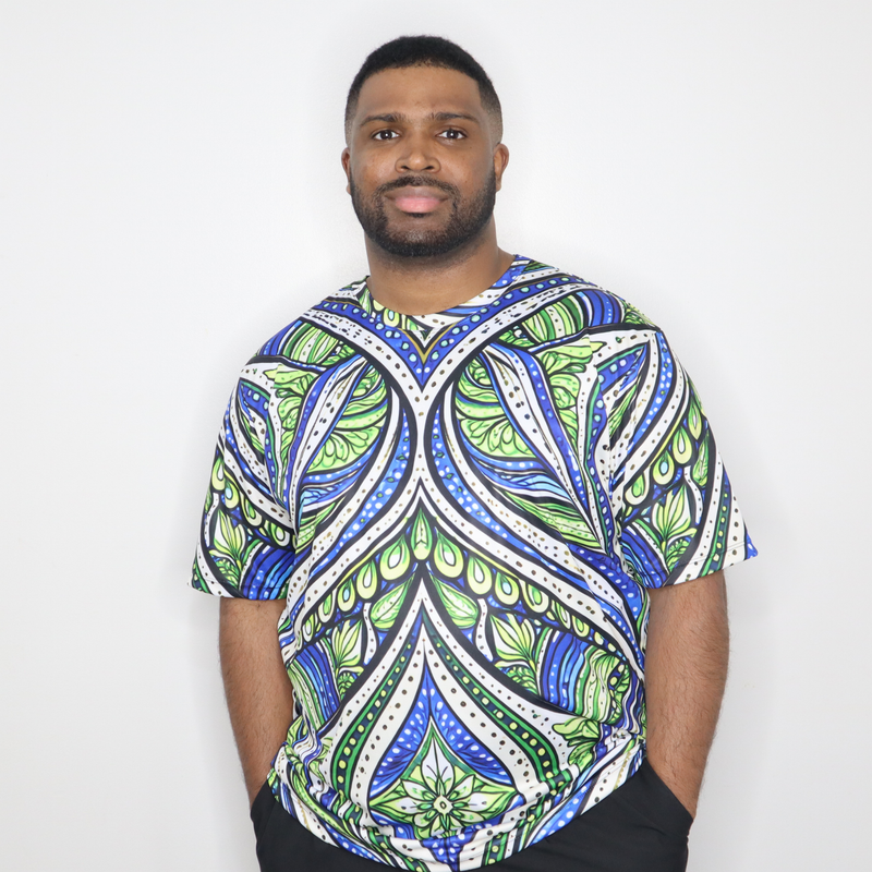 Model shown in a detail view of the print, wearing a t-shirt featuring an all over green white and blue Ankara style leaf ...