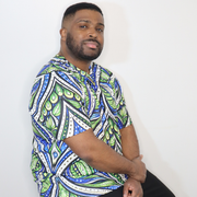 Model shown from the front, wearing a t-shirt featuring an all over green white and blue Ankara style leaf pattern