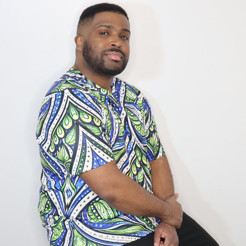 Model shown from the front, wearing a t-shirt featuring an all over green white and blue Ankara style leaf pattern