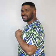 Model shown in side profile, wearing a t-shirt featuring an all over green white and blue Ankara style leaf pattern