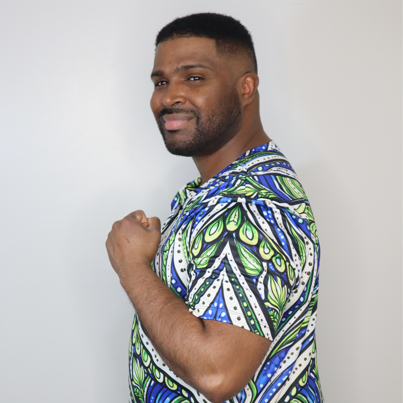 Model shown in side profile, wearing a t-shirt featuring an all over green white and blue Ankara style leaf pattern