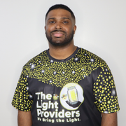 Model shown with arms crossed, wearing a sports jersey featuring a scattered firefly light pattern with The Light Provider...