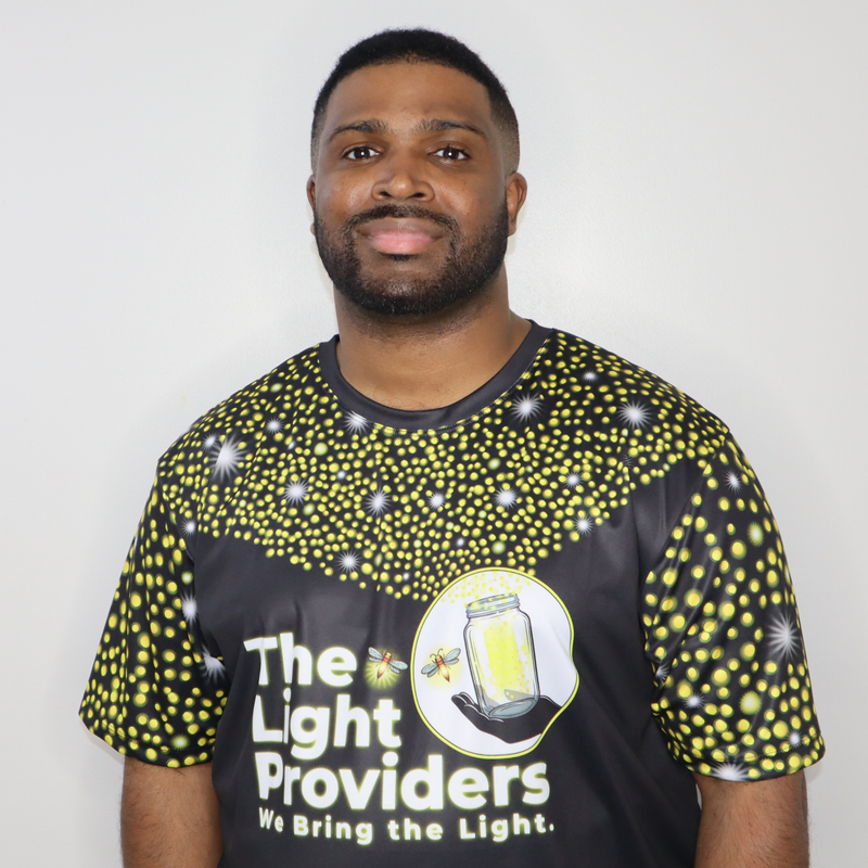 Model shown with arms crossed, wearing a sports jersey featuring a scattered firefly light pattern with The Light Provider...