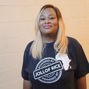 in a detail view of the print, Powered By Jollof Rice stamp design with a white Africa map silhouette on a black t-shirt