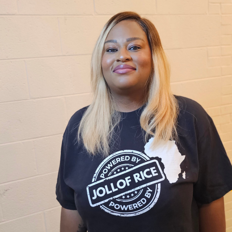 in a detail view of the print, Powered By Jollof Rice stamp design with a white Africa map silhouette on a black t-shirt