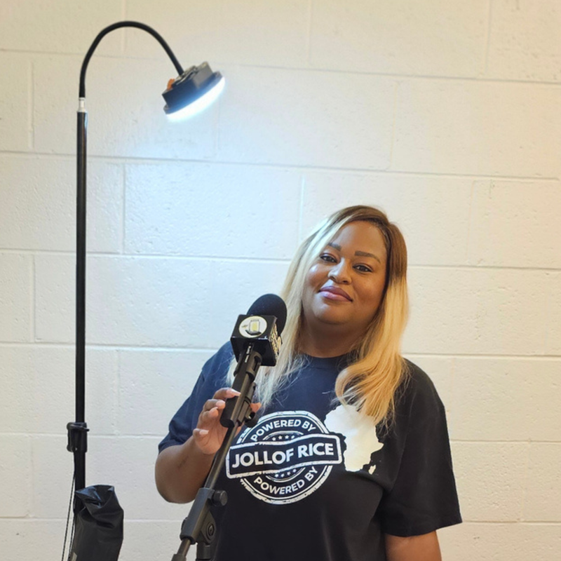 in side profile, Powered By Jollof Rice stamp design with a white Africa map silhouette on a black t-shirt