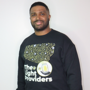 Man wearing a black sweatshirt with 'The Light Providers' logo on a white background