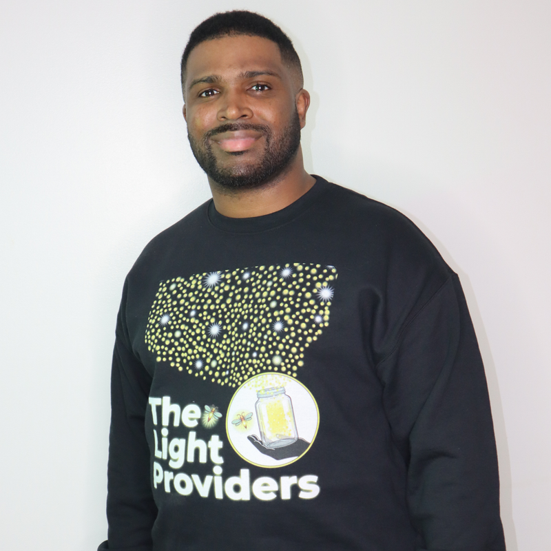 Man wearing a black sweatshirt with 'The Light Providers' logo on a white background