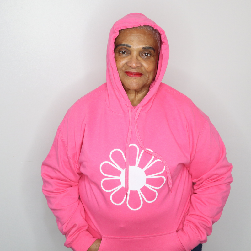 Woman wearing a bright pink hoodie with a white flower design on a plain background designed by The Light Providers
