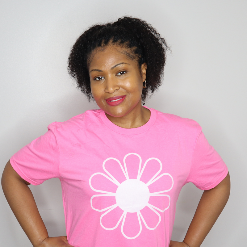 Woman wearing a pink t-shirt with a white flower design on a plain background