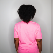 Person wearing a pink shirt from behind on a plain background