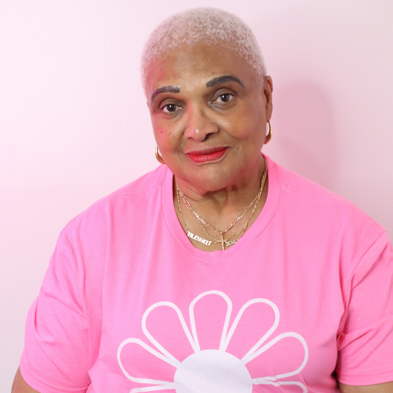Woman wearing a pink shirt with a white flower design on a pink background