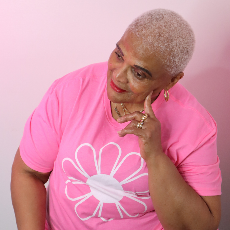 Woman wearing a pink t-shirt with a white flower design against a pink background