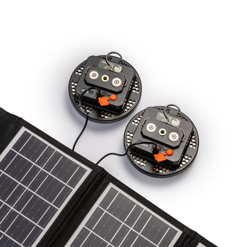 Two wireless light back view being charged by solar panel on white background